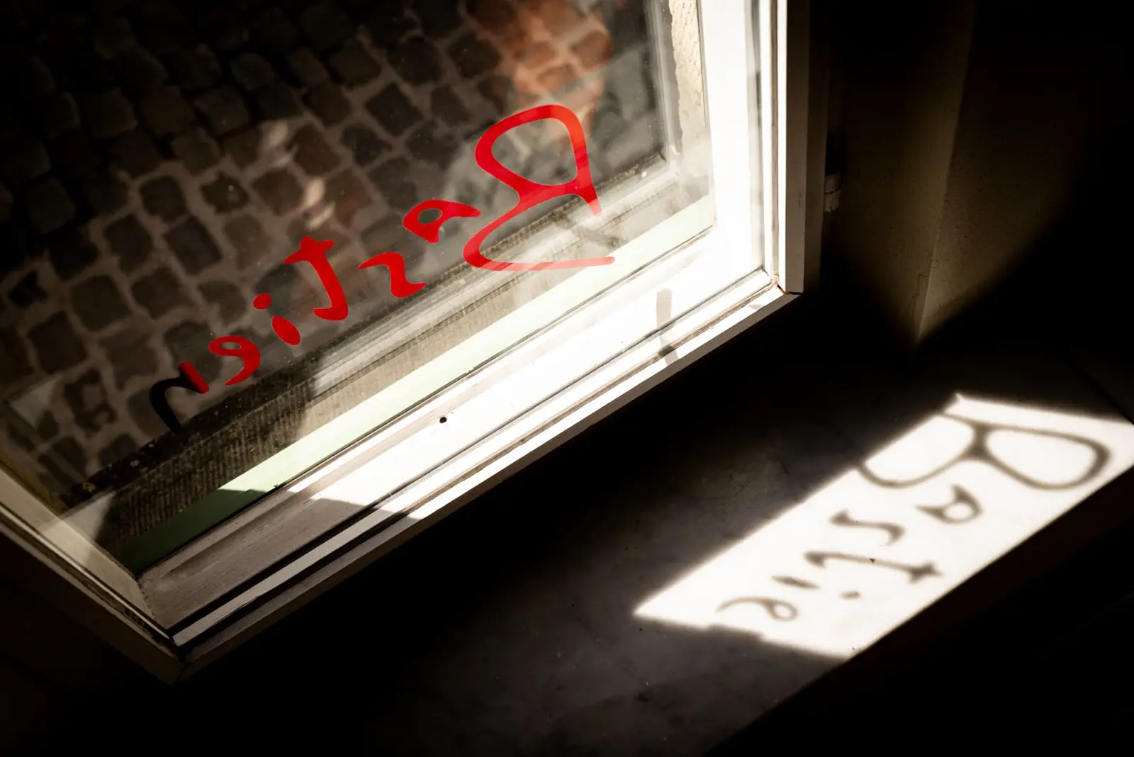 Zonlicht valt door het Bastien-logo op het raam