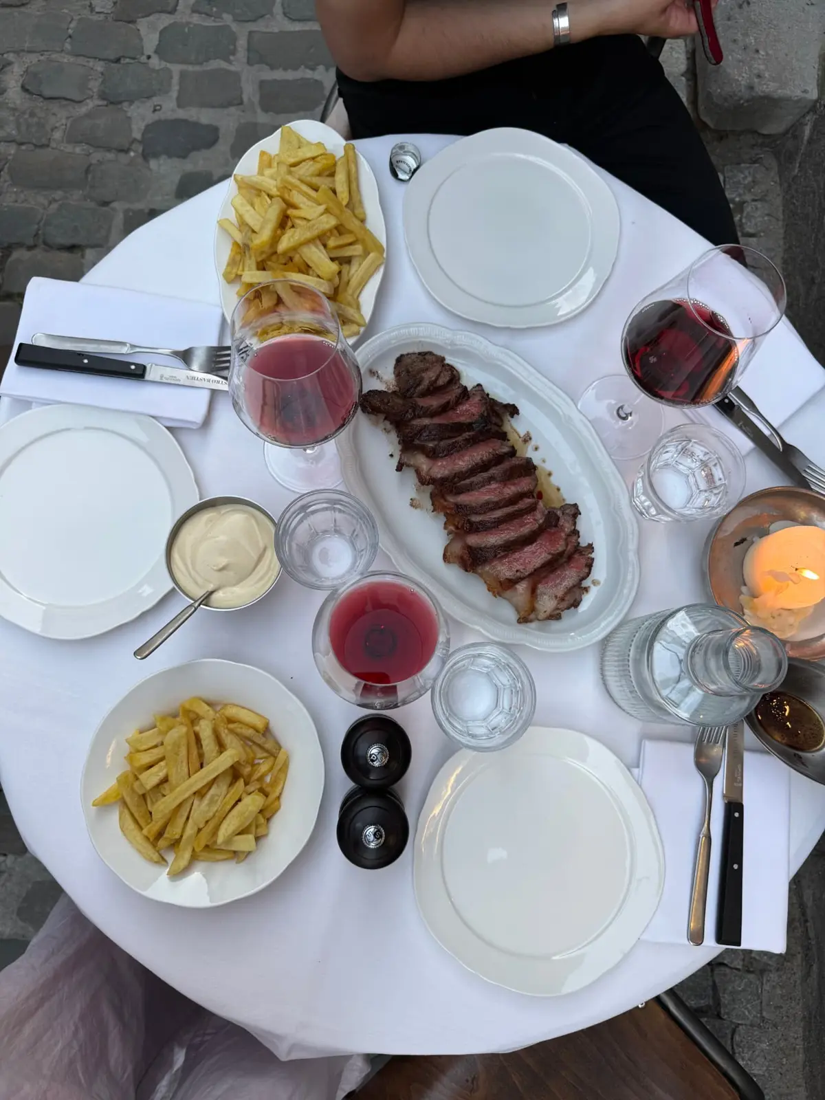 Bovenaanzicht van een tafel met steak, frietjes en rode wijn