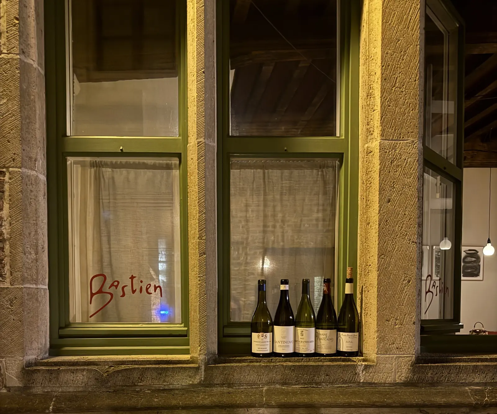 Wijnflessen in het raam met het Bastien-logo