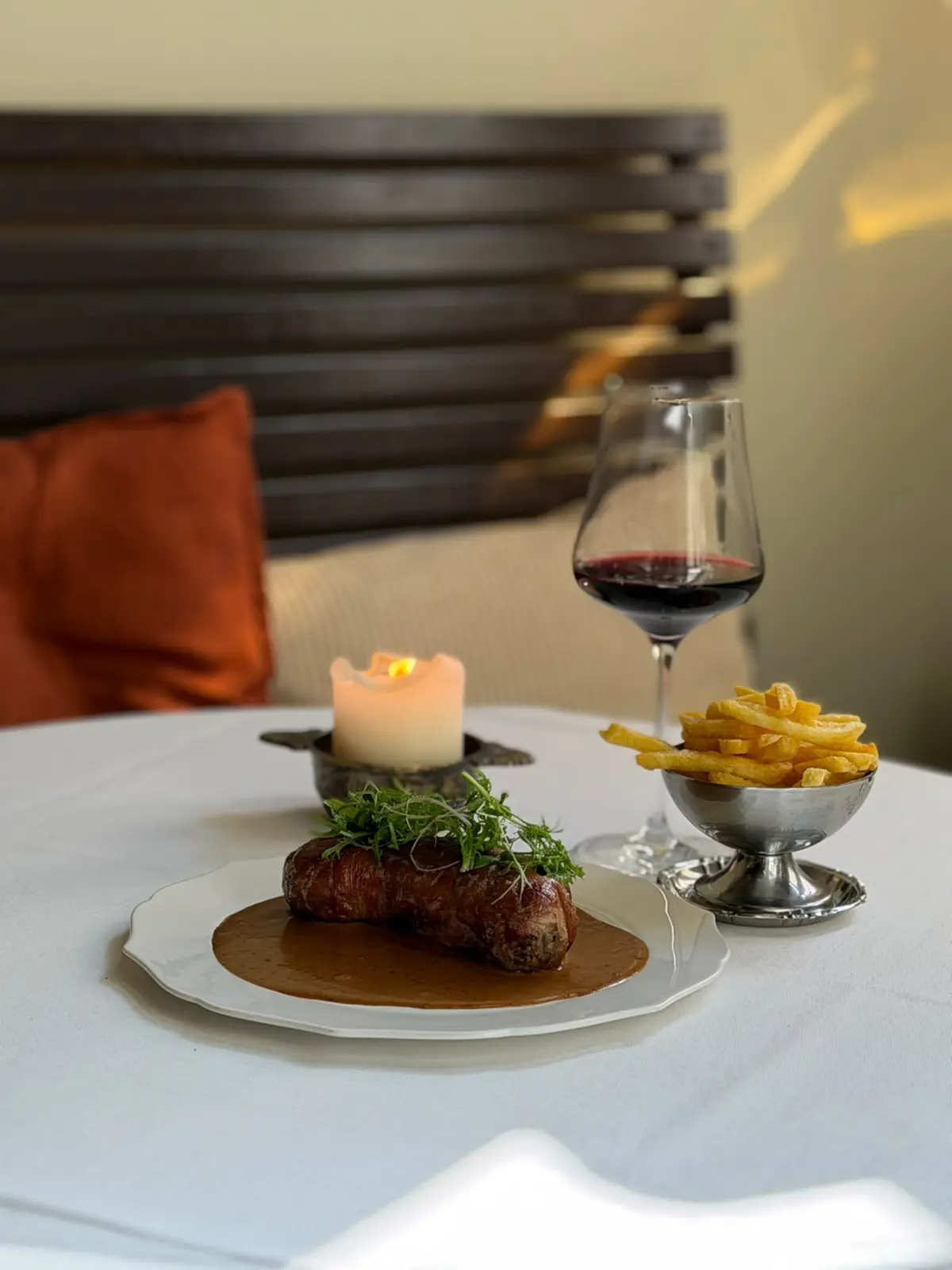 Steak met frietjes en een glas rode wijn bij kaarslicht